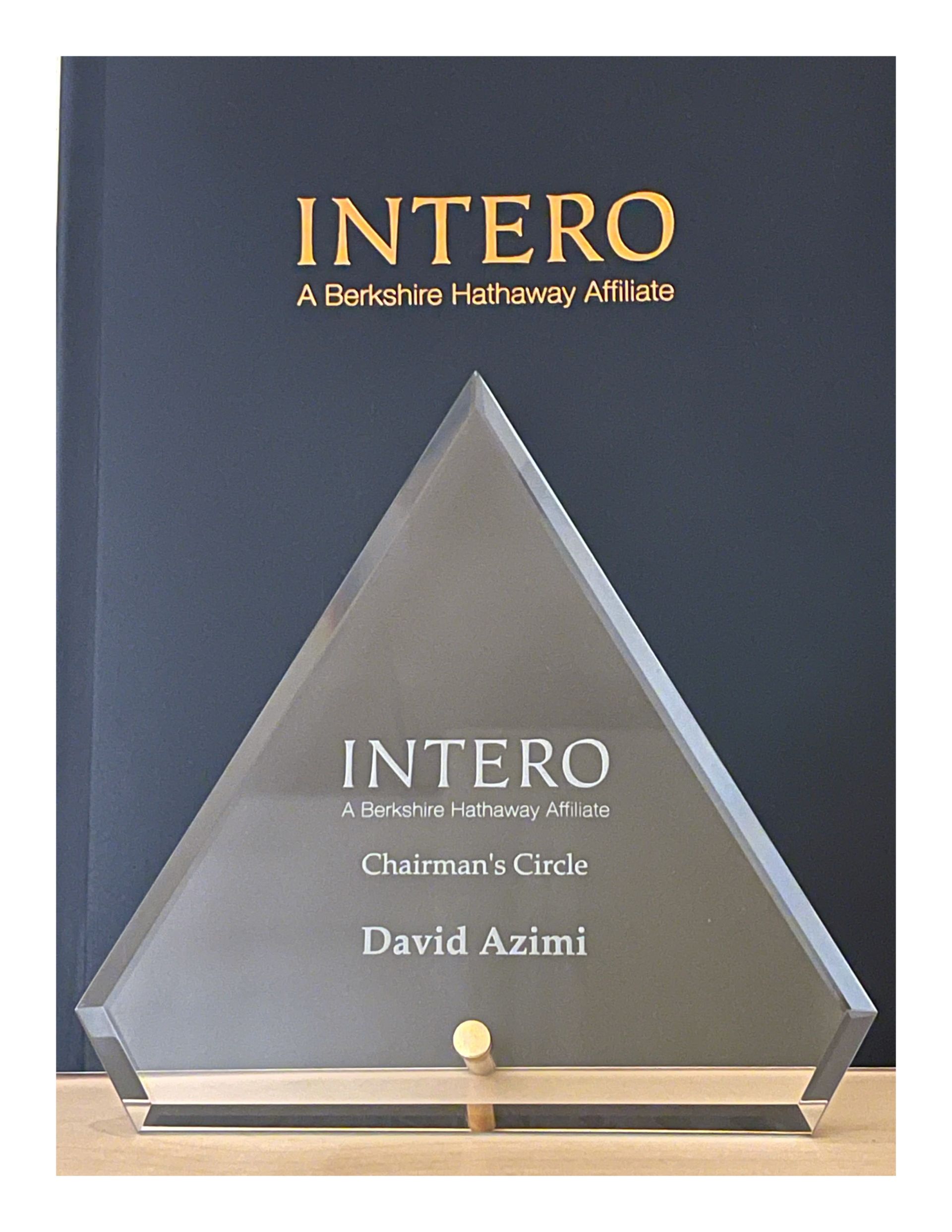 Triangular glass award on a black stand with gold text reading “INTERO” and “David Azimi”