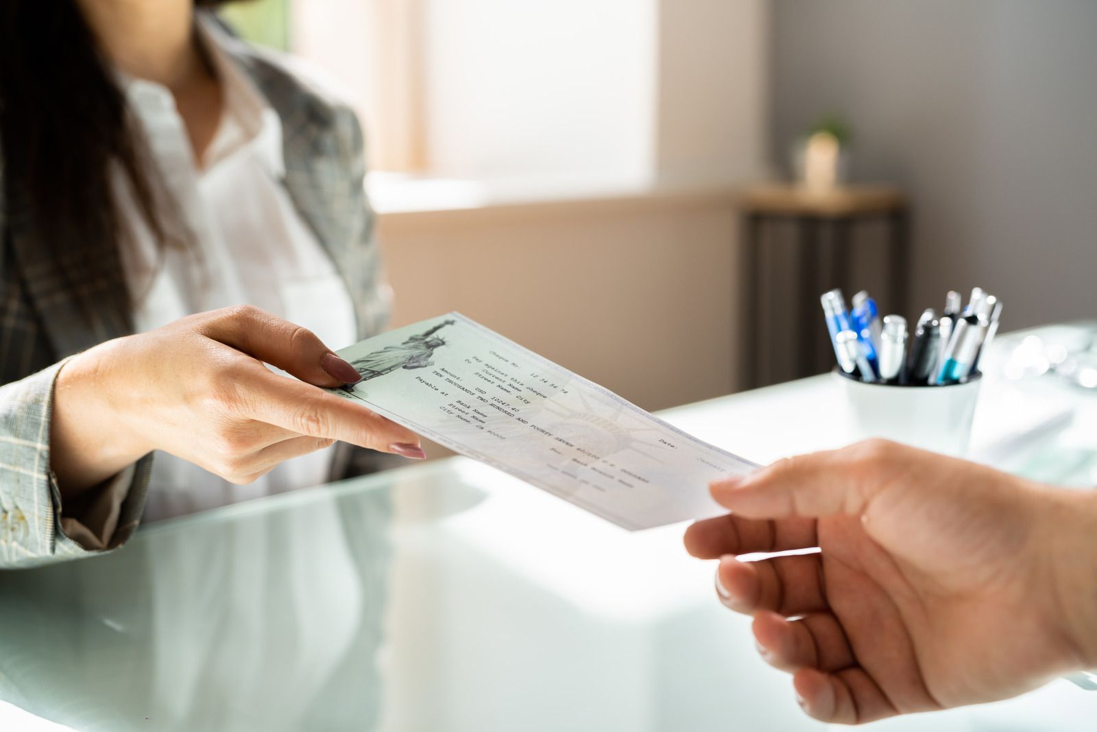 A man is handing a check to a woman at a desk.