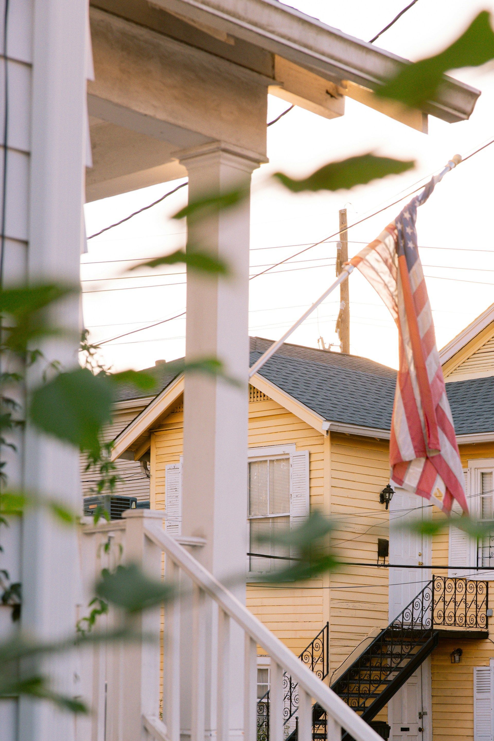 An american flag is flying on the porch of a house.