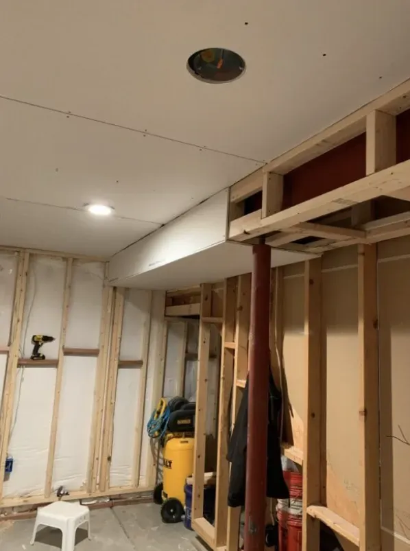 Basement construction: drywall ceiling with recessed light, wooden framing, red support column.