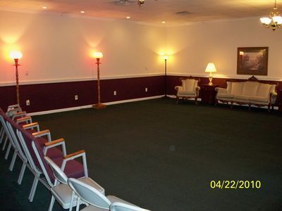 Empty conference room with chairs along the wall, lamps, and a small table with a bust statue.