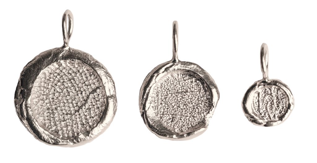 Three round silver pendant charms of different sizes on a white background