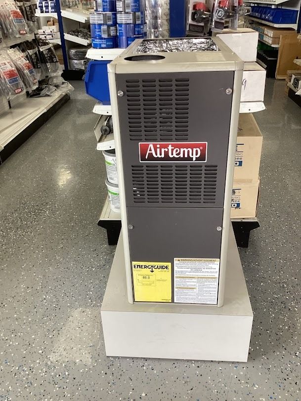 Gray Airetemp furnace unit on display in a store aisle, sitting on a white pedestal.