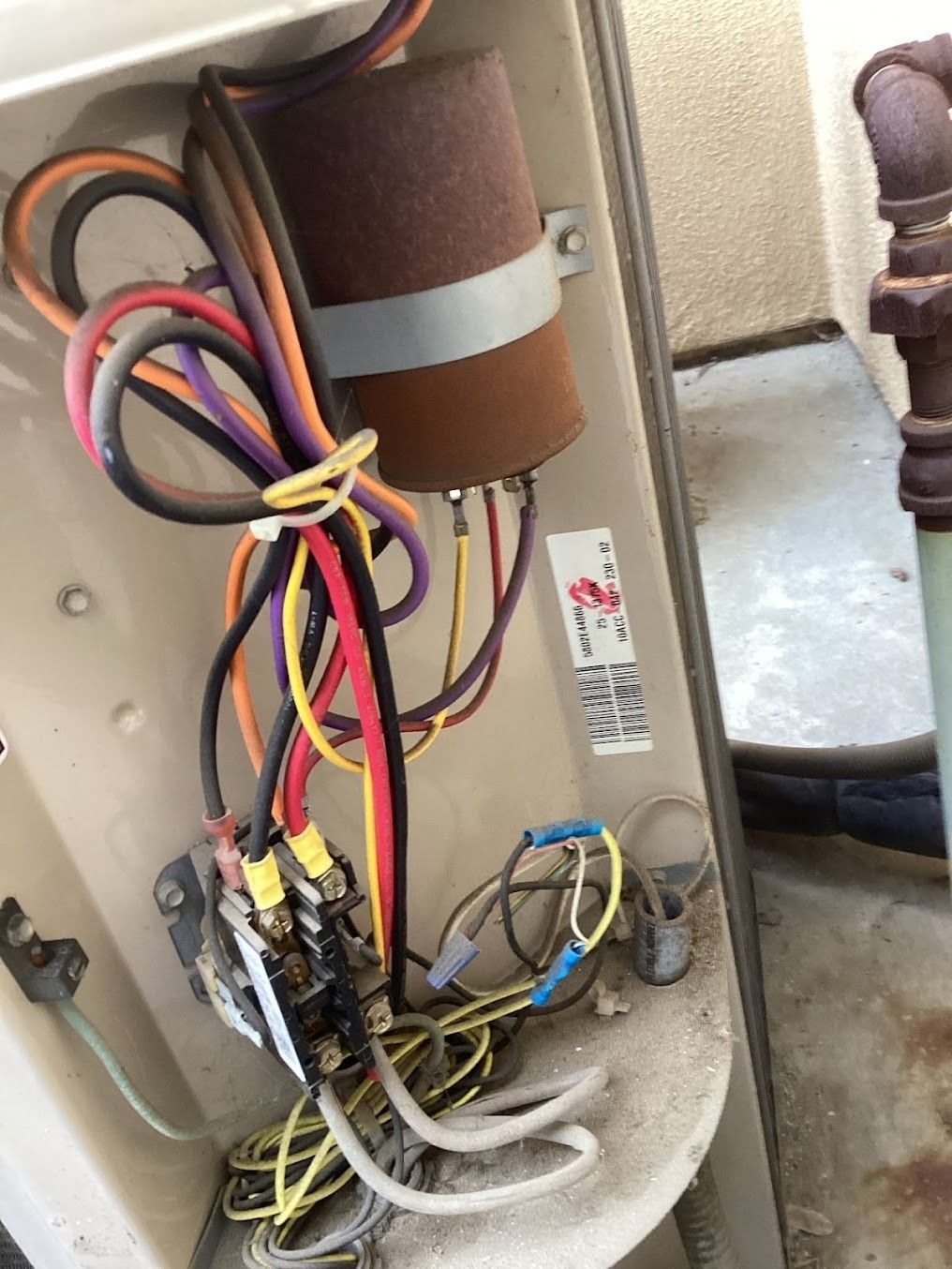Open electrical panel with exposed wires, cables, and components inside a beige metal cabinet.