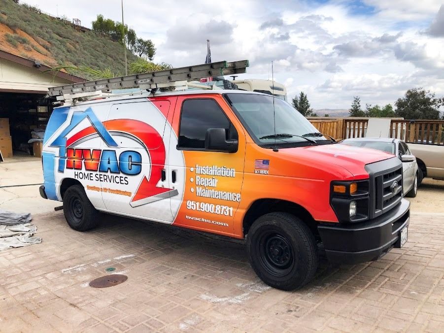 Orange and white service van parked outdoors with large logo and ladder on roof