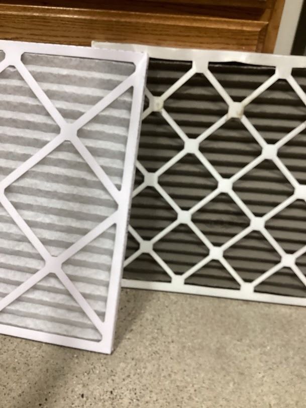 Two white decorative lattice panels leaning on a carpeted floor indoors