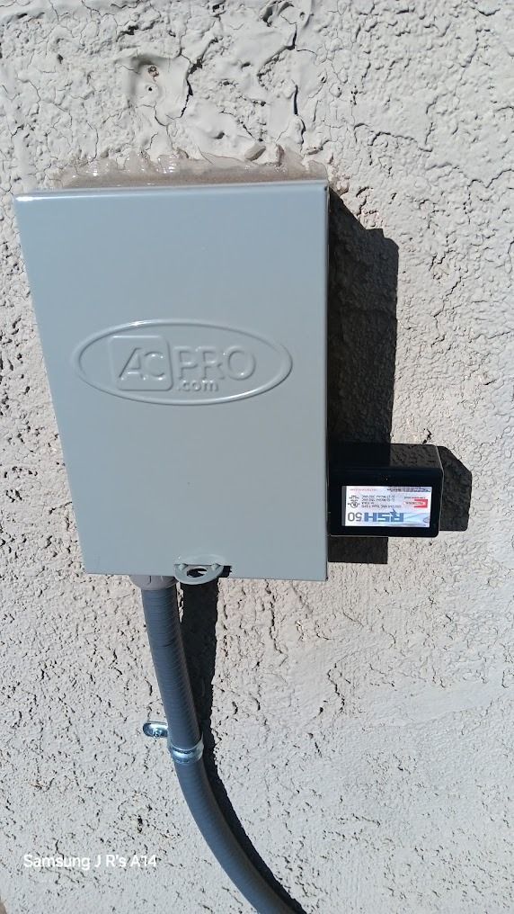 Gray electrical box mounted on a stucco wall with a small meter attached on the right