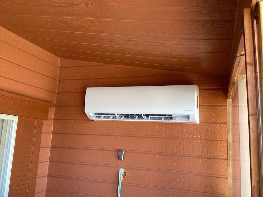 White wall-mounted air conditioner on an orange-brown wooden exterior wall.