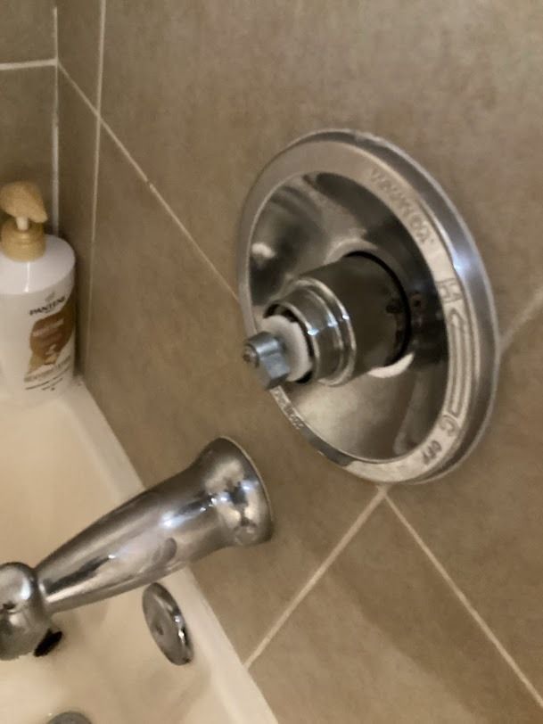 Chrome shower faucet and diverter handle on beige tiled bathroom wall