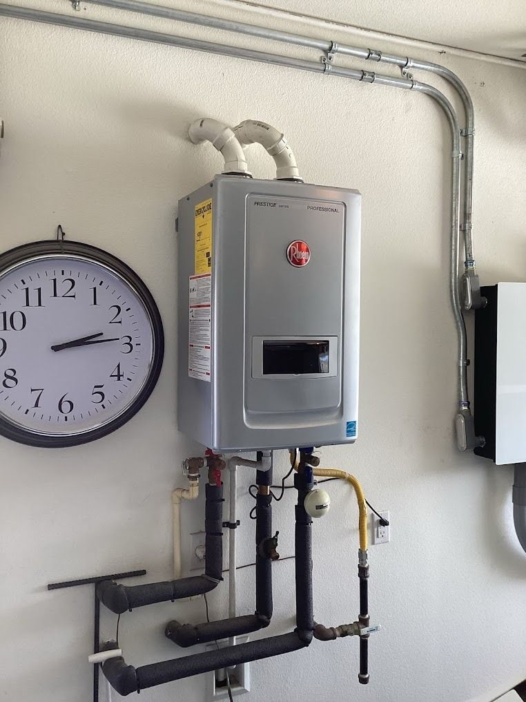 Wall-mounted gray utility unit with pipes beside a clock in an indoor room.