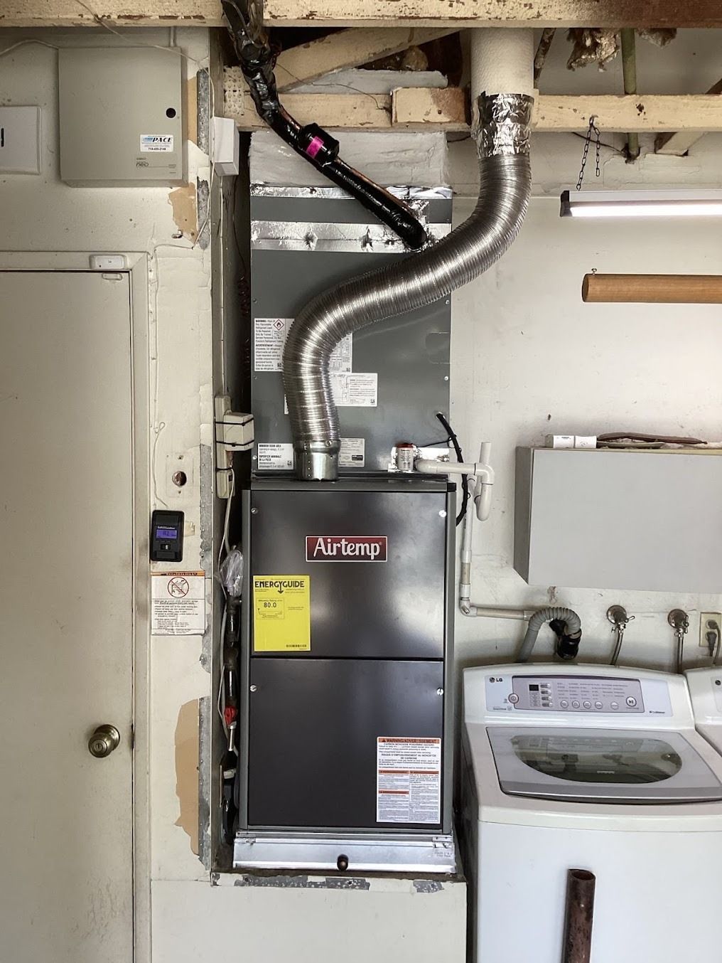 Indoor utility closet with furnace, ductwork, water heater, and electrical panel
