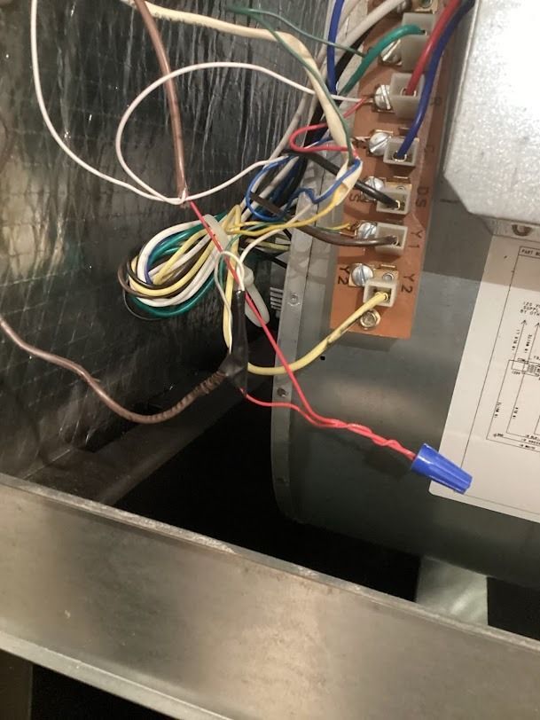 Close-up of electrical wiring and terminal strip inside a metal HVAC cabinet.