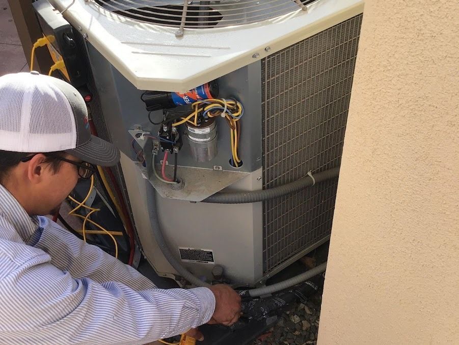 Technician servicing an outdoor HVAC unit with exposed wiring and open panels