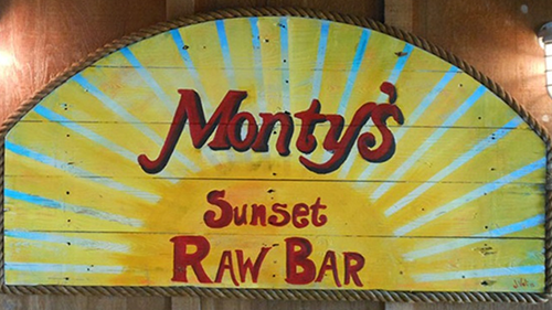 A yellow sign that says monty 's sunset raw bar
