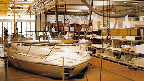 A boat is being built in a factory behind a fence