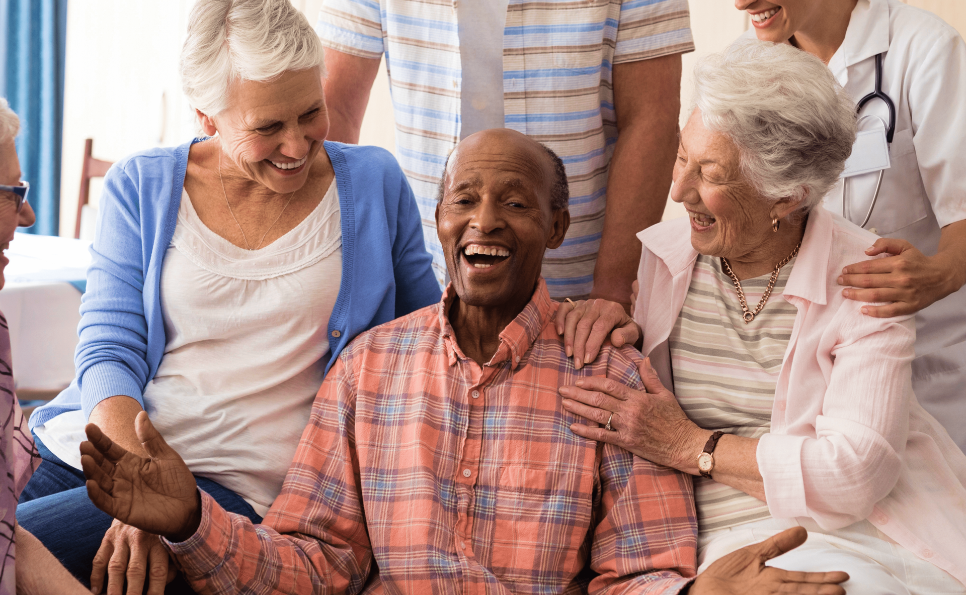 A group of elderly people are sitting on a couch and laughing.