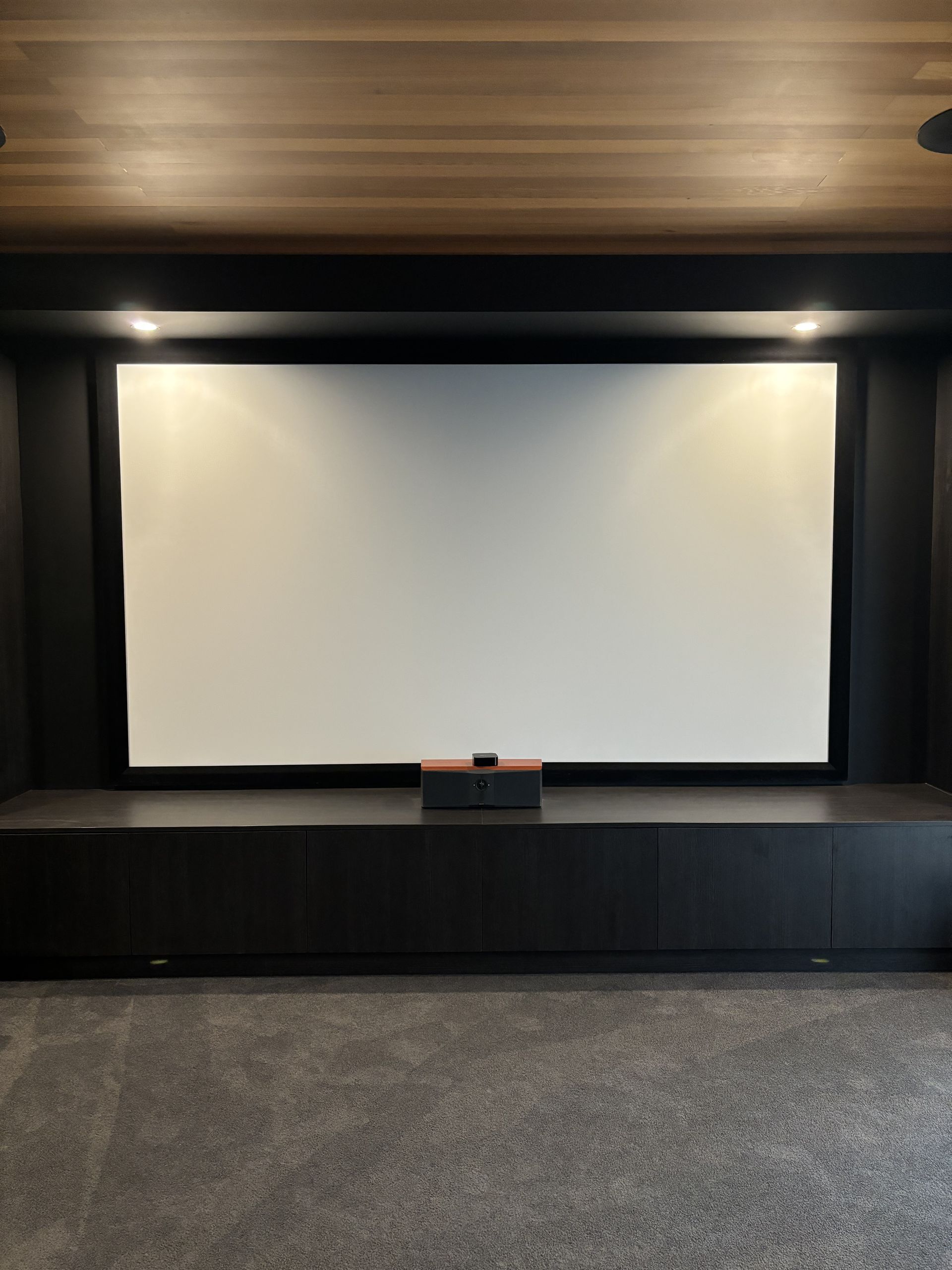 A theatre room with a large movie screen and black cabinets — Darko's Kitchens in Albion Park Rail, NSW