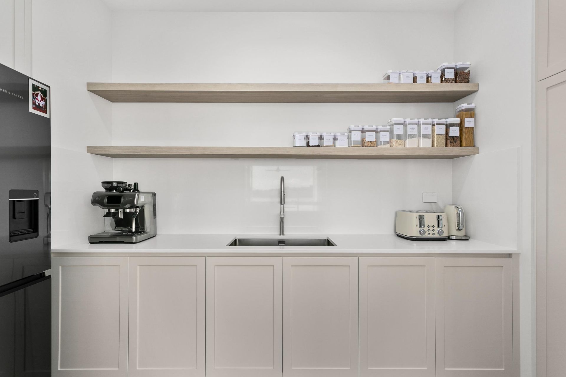 A Kitchen With White Cabinets and Wooden Shelves Filled With Jars — Darko's Kitchens in Albion Park Rail, NSW