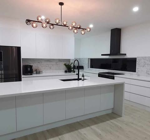 A Kitchen With White Cabinets, a Sink, a Refrigerator, and a Chandelier — Darko's Kitchens in Albion Park Rail, NSW