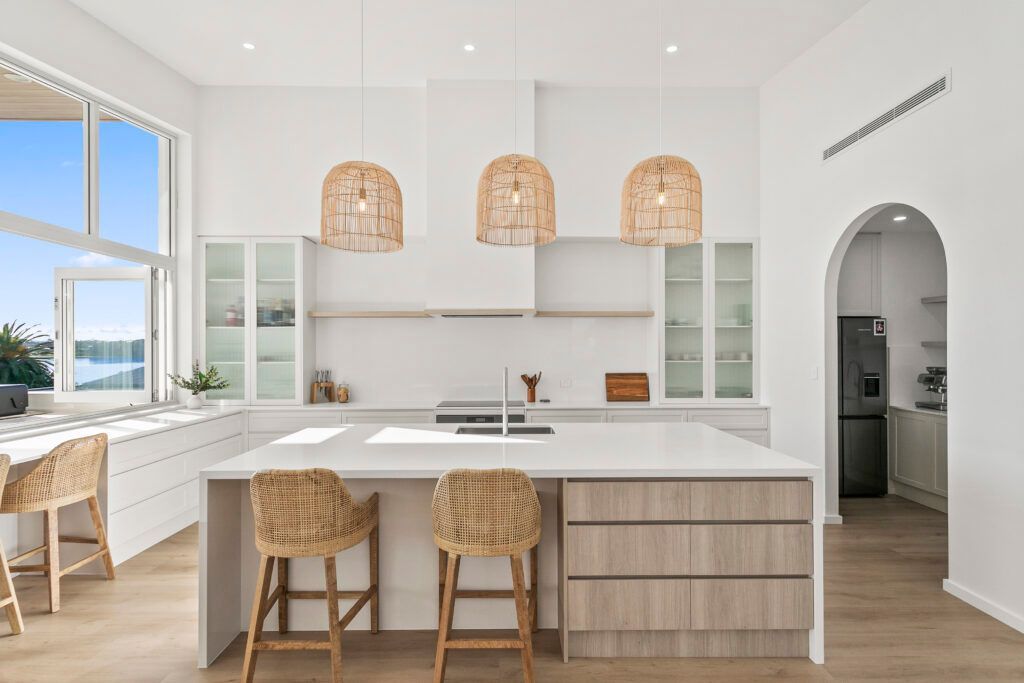 Bright, Coastal-style Kitchen Featuring a Large White Island With Light Wood Drawers — Darko's Kitchens in Primbee, NSW