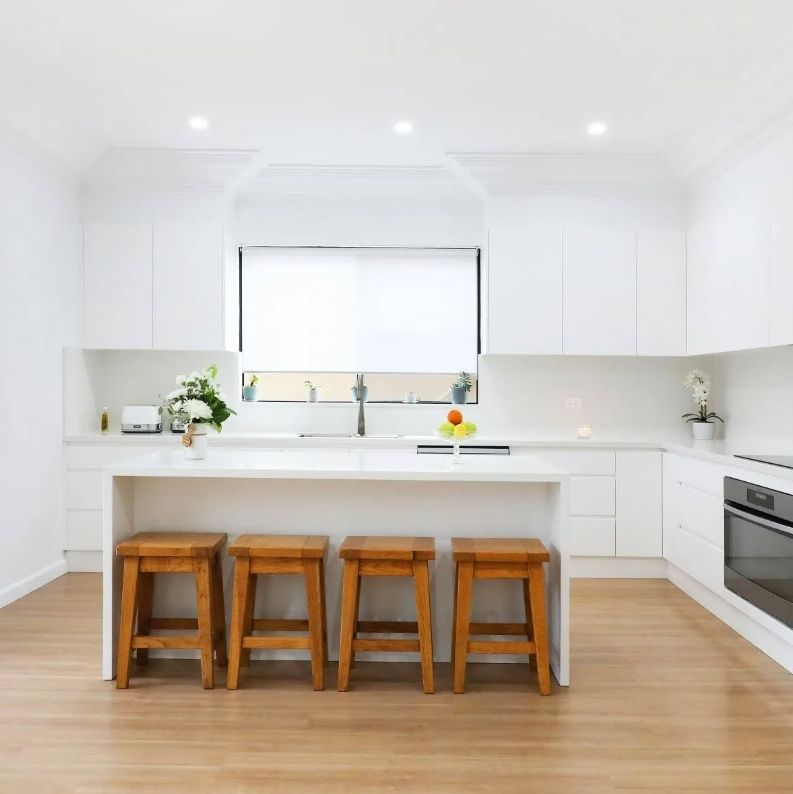 A Kitchen With White Cabinets and Wooden Stools — Darko's Kitchens in Southern Highlands, NSW