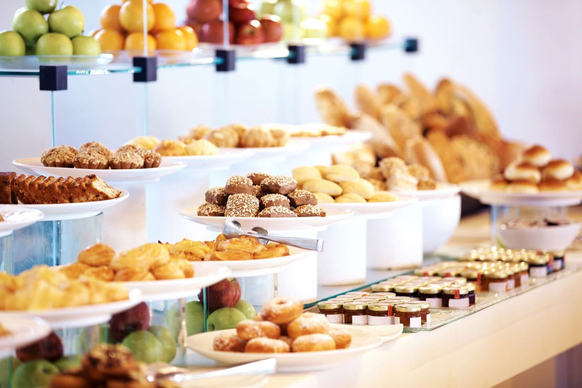 Buffet with baked goods and fruit displayed on tiered shelves.
