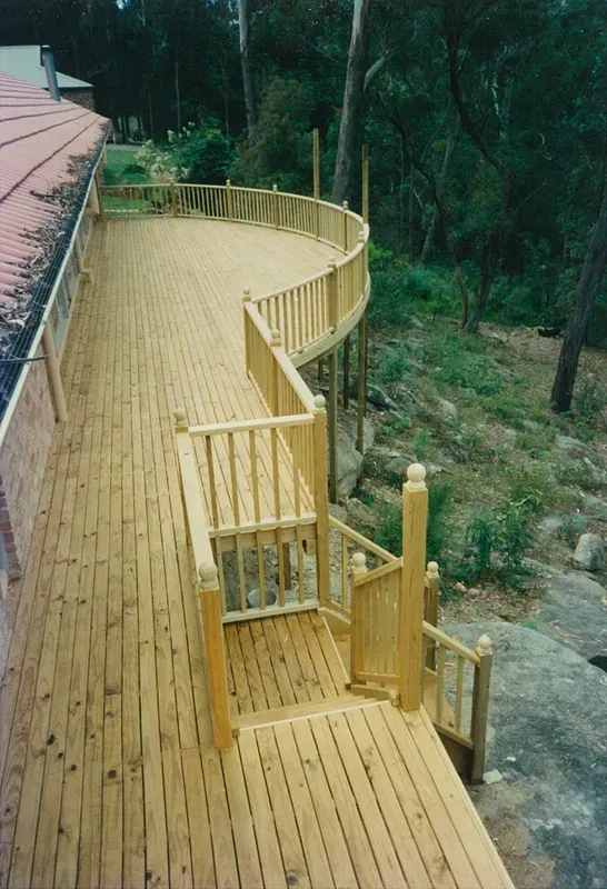 Curved Wooden Boardwalk with Railings Along a Forested Hillside — Boyne Building & Renovations in Ponto, NSW