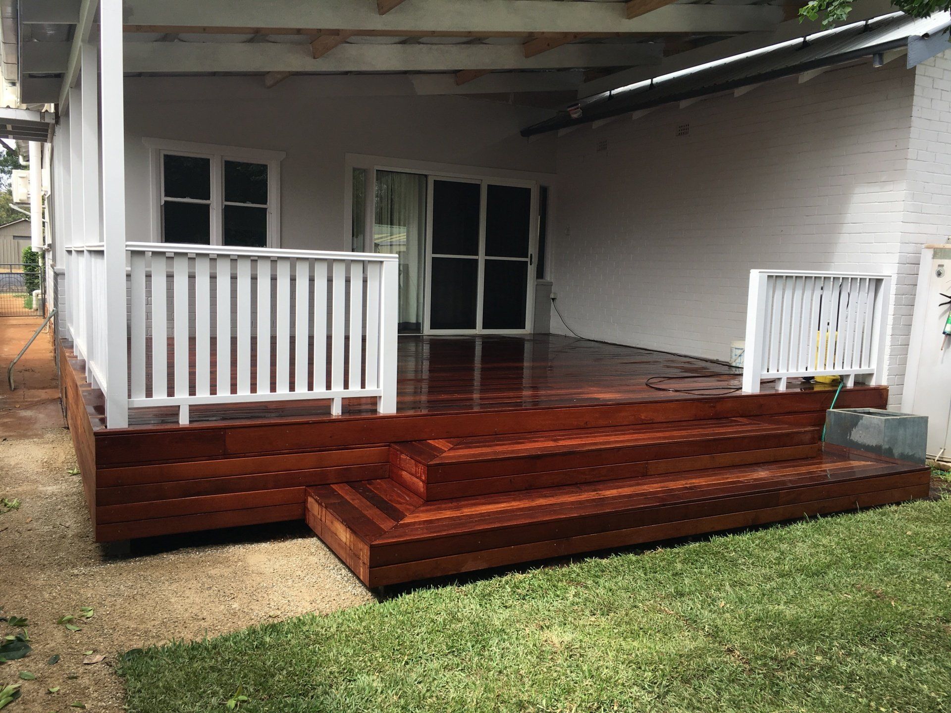 Covered Wooden Deck with White Railings and Steps Leading to A House Patio — Boyne Building & Renovations in Ponto, NSW