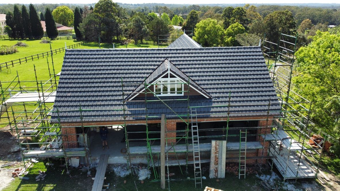 Partially built house with dark roof in a green rural landscape