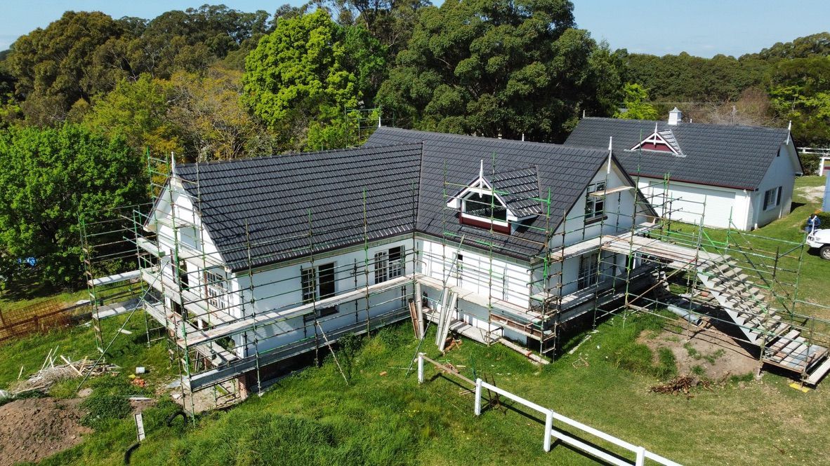 Aerial view of white Victorian-style houses with dark roofs, surrounded by trees and grass