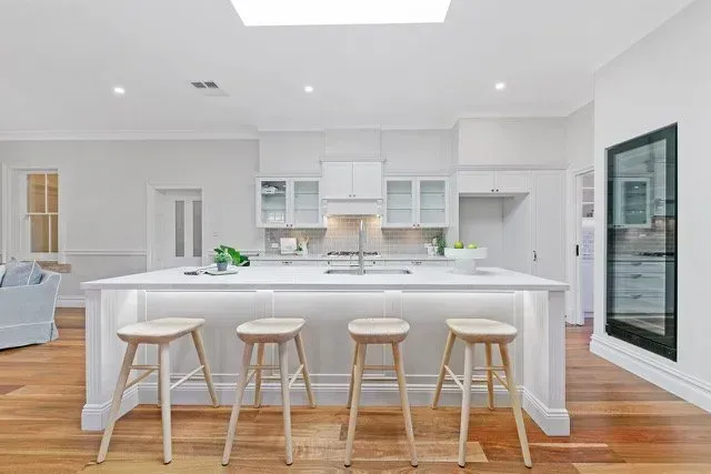Bright White Kitchen with Island and Four Stools, Hardwood Floors — Boyne Building & Renovations in Ponto, NSW