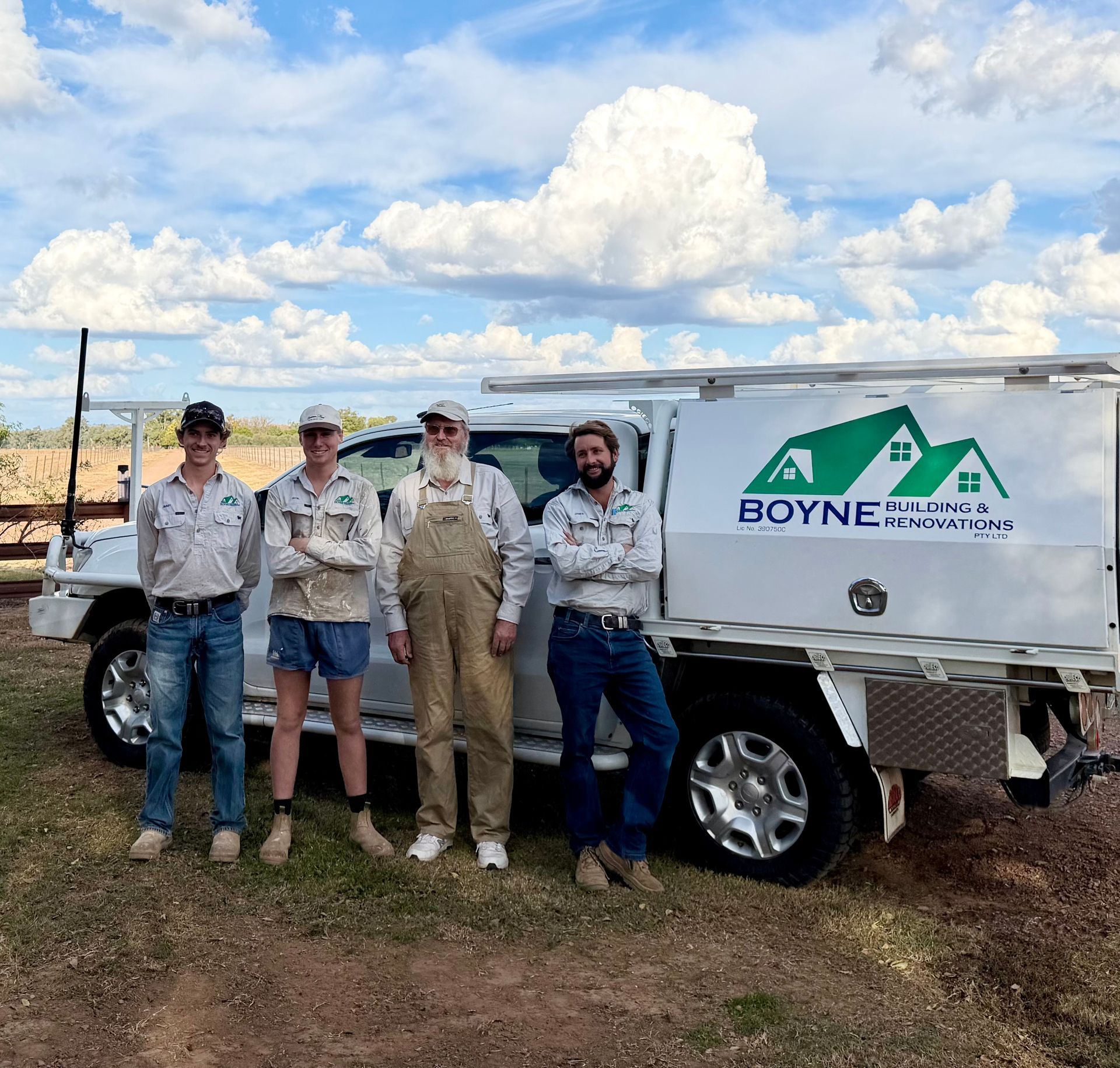 Four workers in work clothes stand beside a white Boyne Mountain service truck under a cloudy sky.