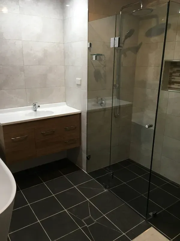 Modern Bathroom with Dark Tile Floor, White Sink, Wood Vanity — Boyne Building & Renovations in Ponto, NSW