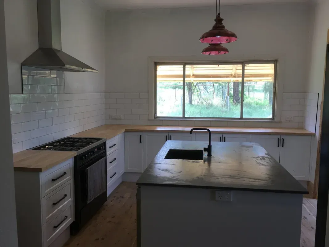 Modern Kitchen with White Cabinets, Black Island Countertop — Boyne Building & Renovations in Ponto, NSW