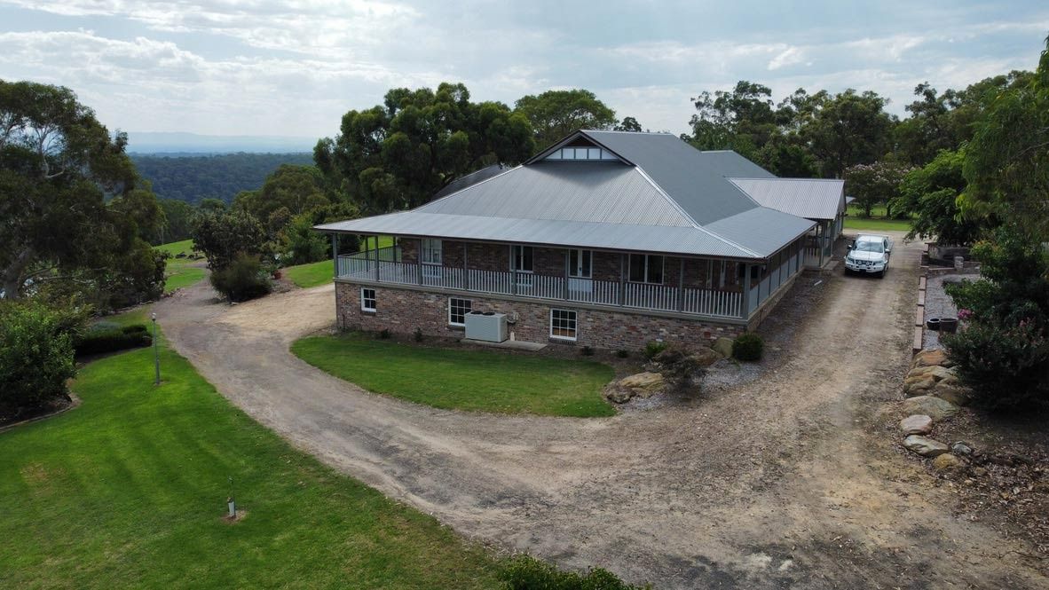 A Stone House With a Gray Roof on a Dirt Driveway — Boyne Building & Renovations in Ponto, NSW
