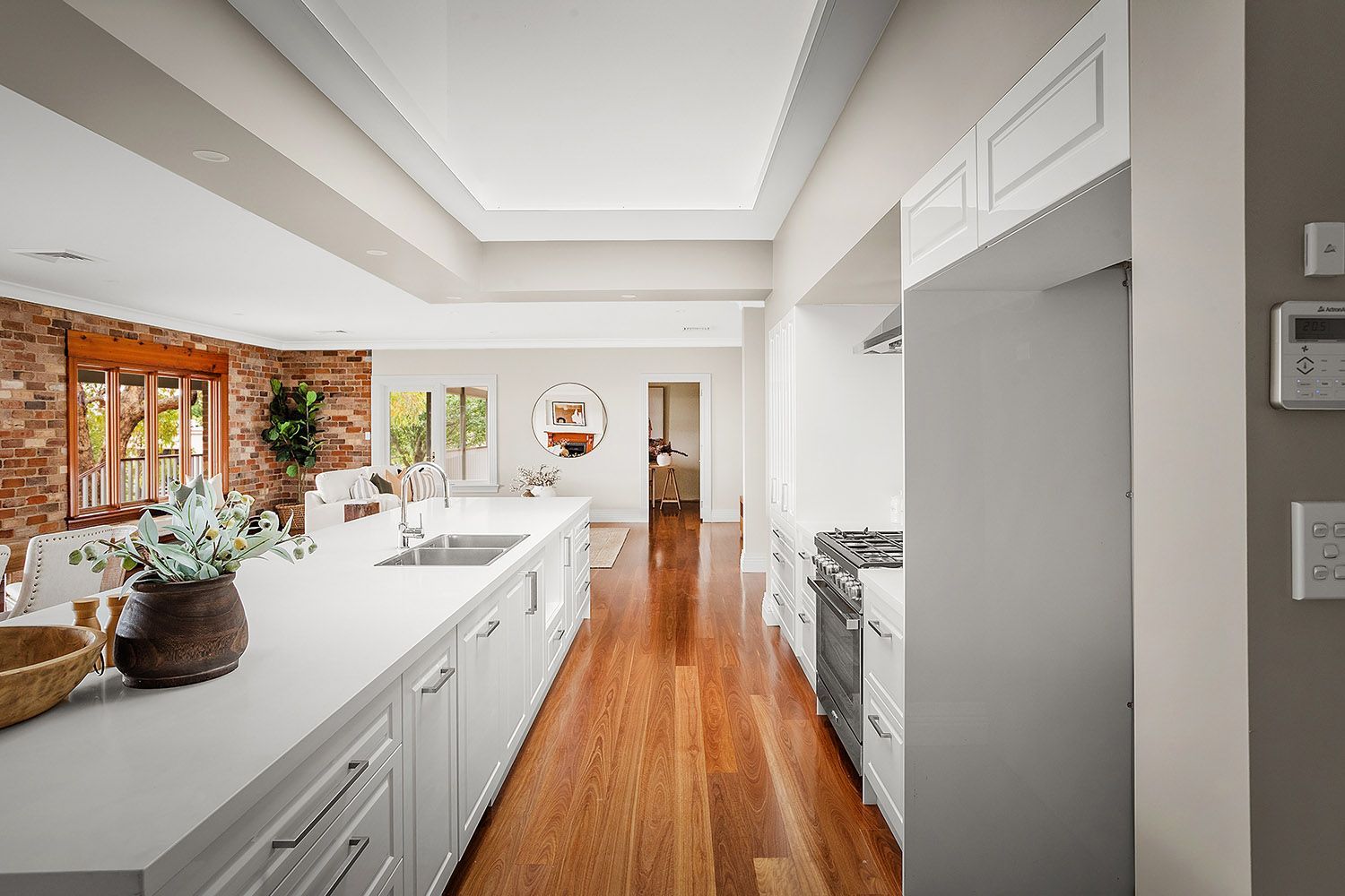 Bright White Kitchen With Island, Wood Floors, and Large Windows — Boyne Building & Renovations in Ponto, NSW