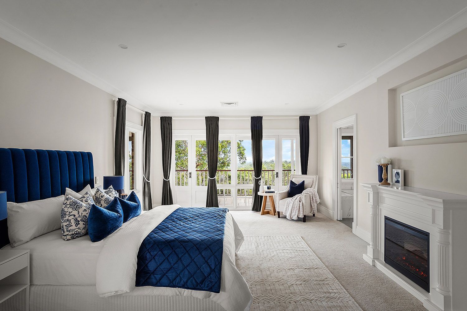 Bright Bedroom With Blue Accents, Fireplace, and Balcony Doors — Boyne Building & Renovations in Ponto, NSW