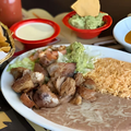 Plate of Mexican food with rice, refried beans, grilled meat, tortilla chips, and salsa on the side