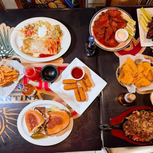 Overhead view of a table with tacos, burgers, fries, nachos, wings, and drinks