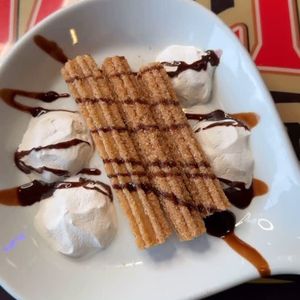 Dessert plate with waffle fingers, whipped cream scoops, and chocolate drizzle