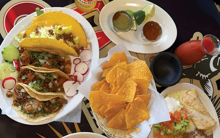 Assorted tacos, chips, salsas, and drinks arranged on a festive table