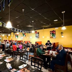 Busy Mexican restaurant with diners seated at tables under warm yellow walls and hanging lights