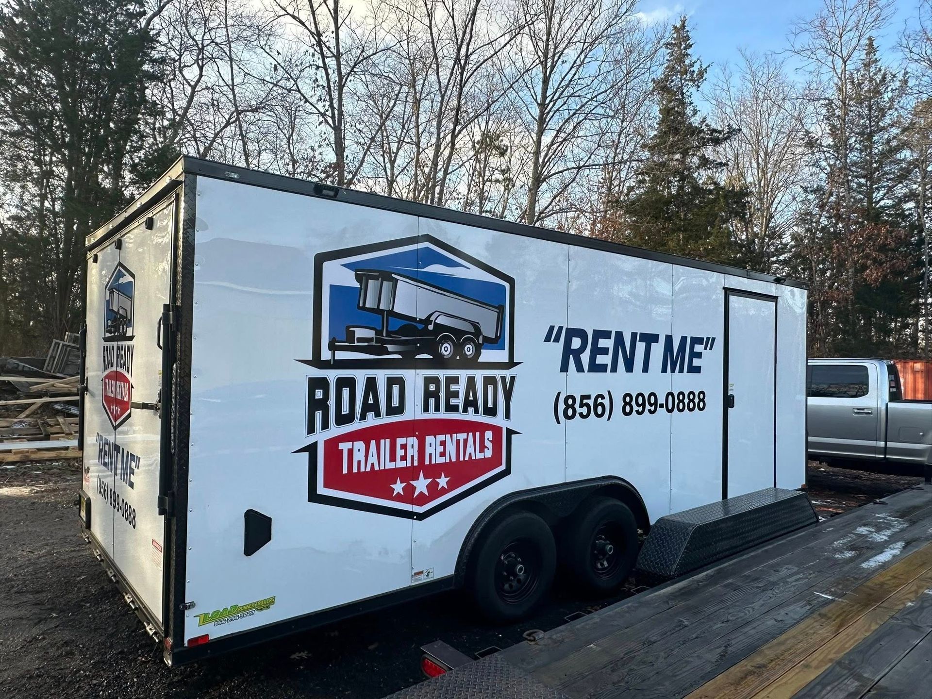 A white Road Ready trailer parked outdoors with a blue and red logo, the words 