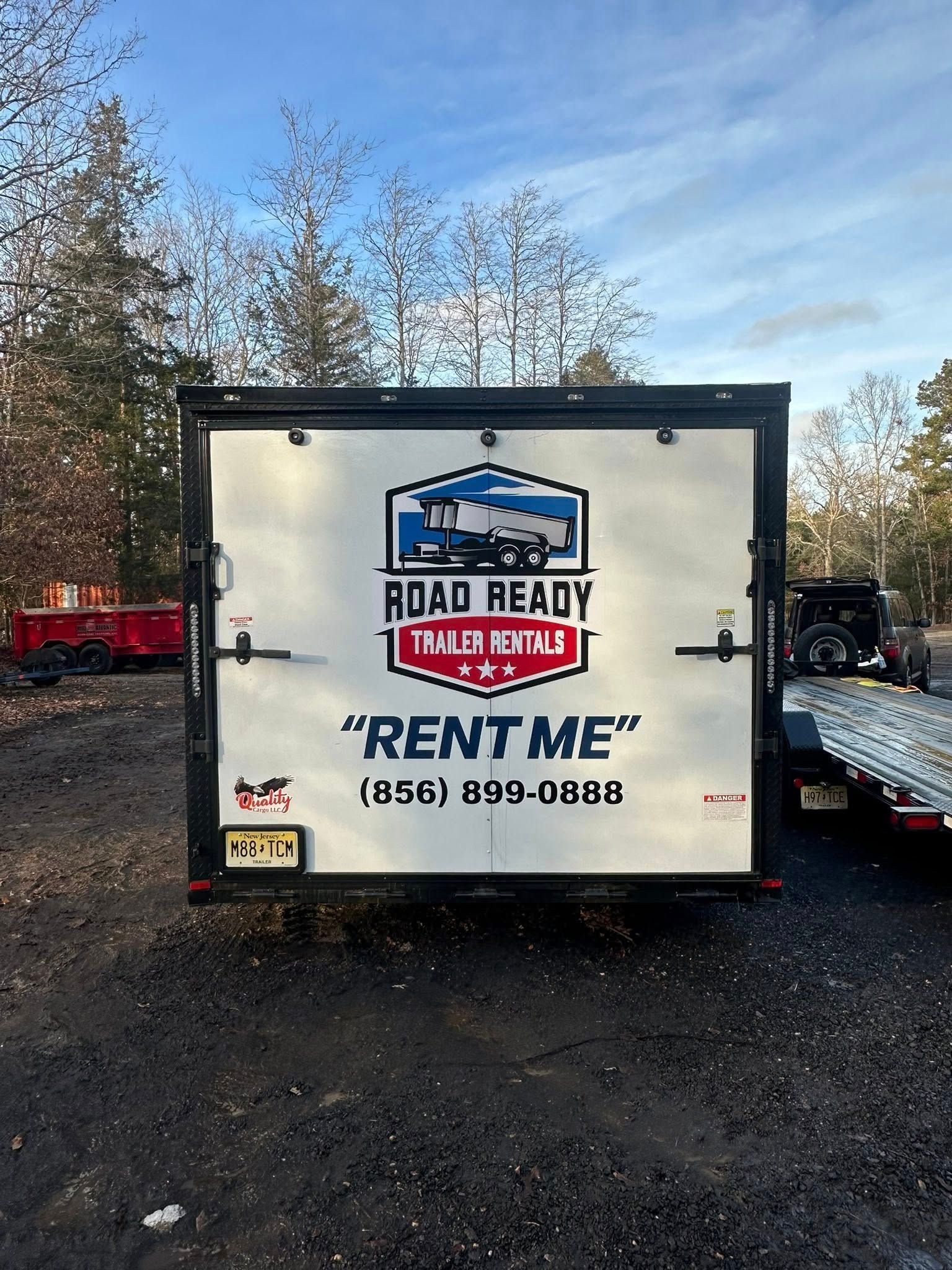 The back of a white Road Ready Trailer Rental trailer with the phone number (856) 899-0388 parked in a gravel lot.