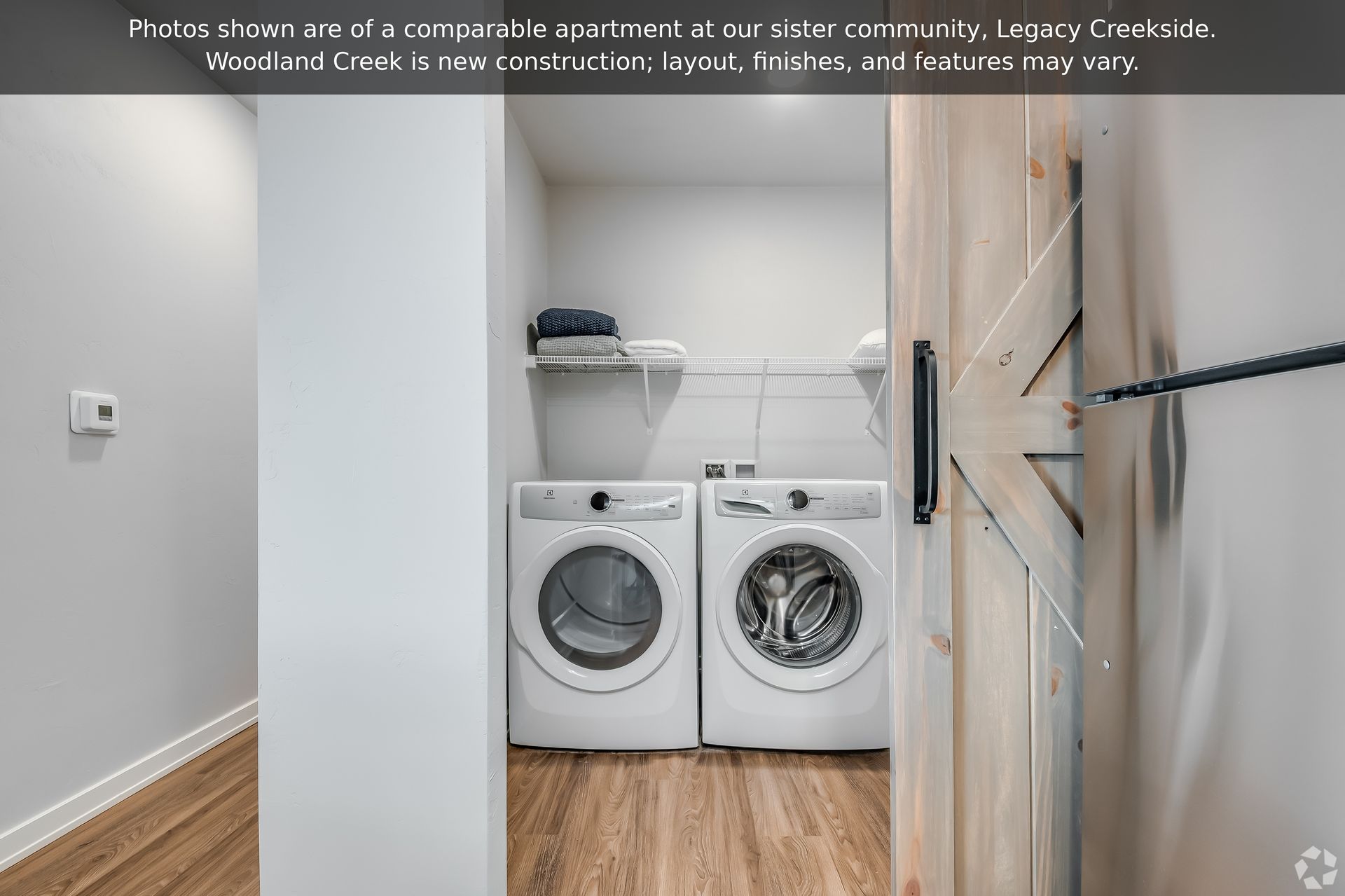 Laundry nook with stacked front-load washer and dryer beside a wood sliding door