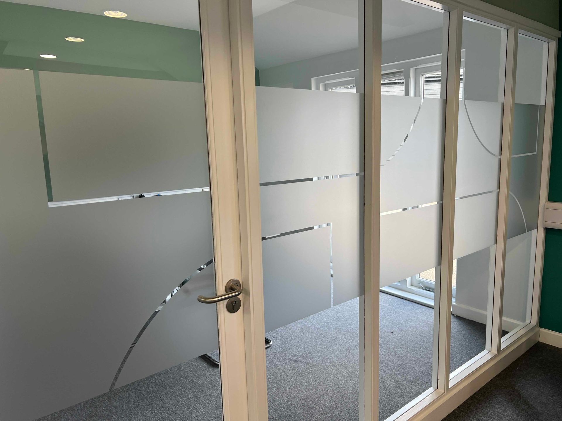 Meeting room glass partition with frosted privacy manifestations