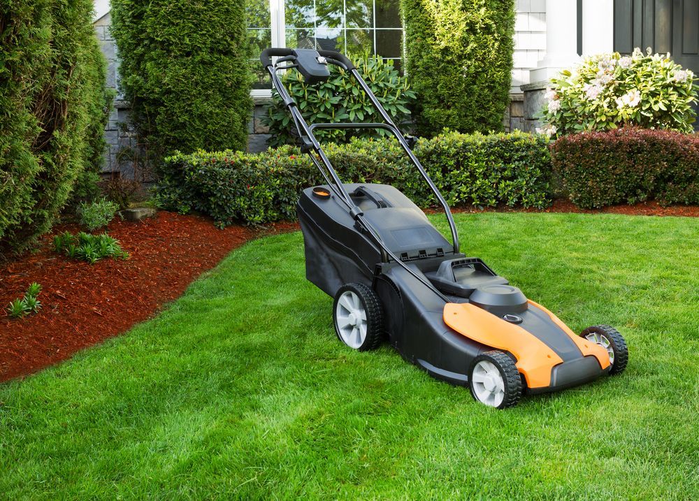 A Black and Orange Lawnmower on a Green Lawn in Front of a House — Integral Cleaning Services in Maitland, NSW