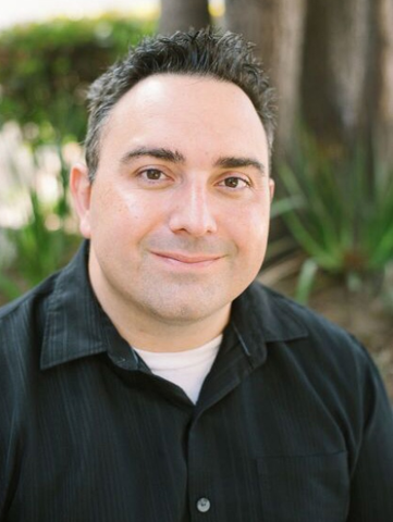 A man in a black shirt is smiling for the camera.