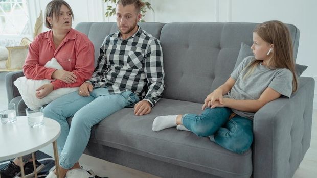 A family is sitting on a couch talking to each other.