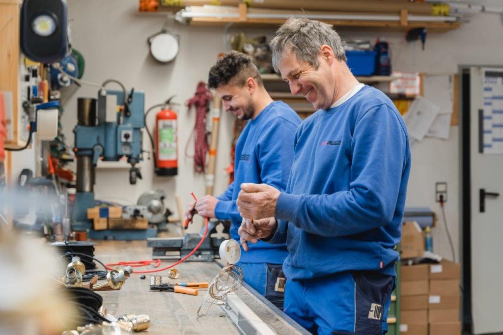Zwei Männer arbeiten in einer Werkstatt an einer Maschine.